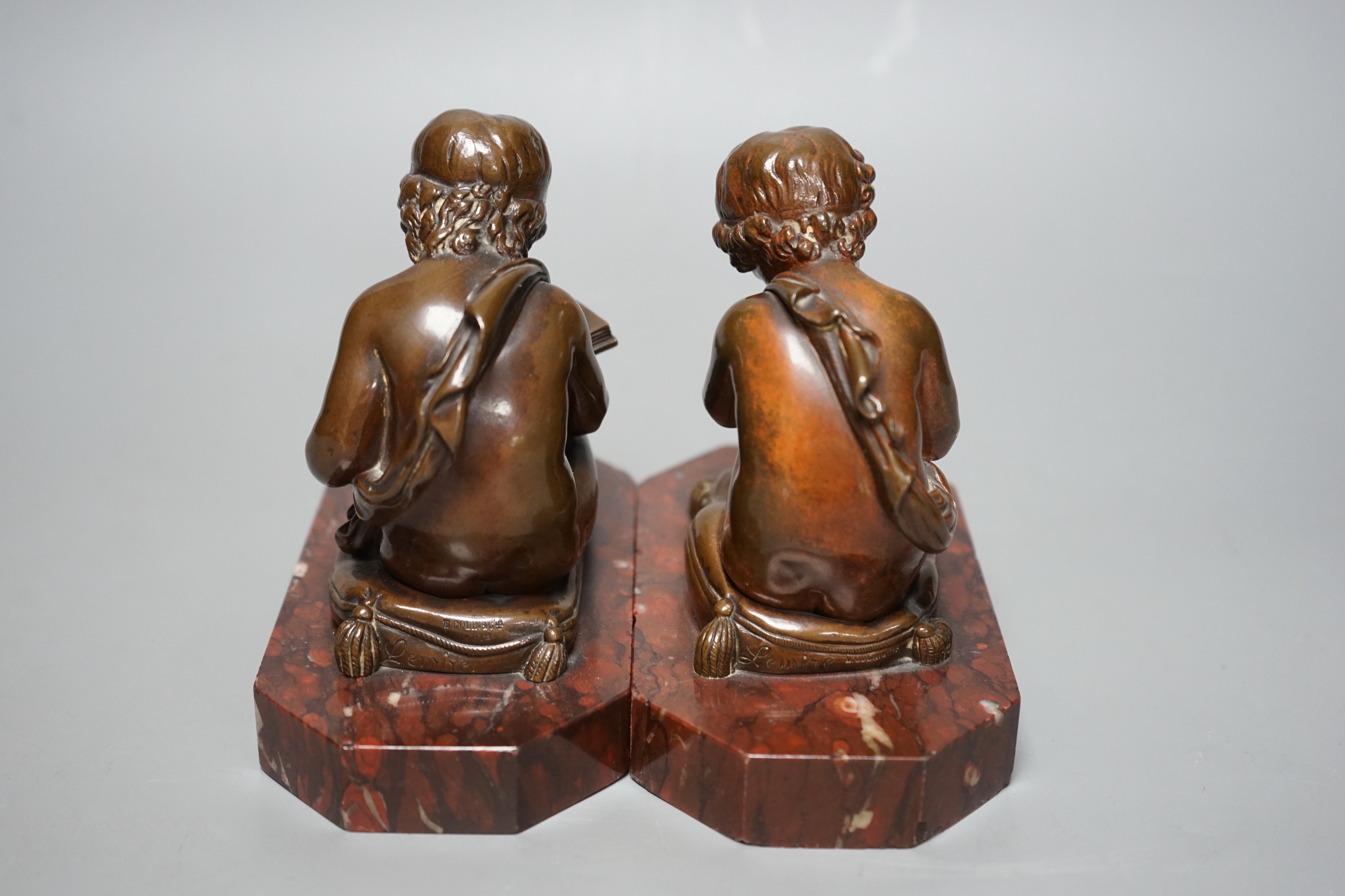 After Charles Gabriel Lemire (1741-1827), a pair of bronze studies of boys seated on cushions, writing and reading, E. Colin & Cie, Paris foundry marks, on rouge marble bases, 14cm long